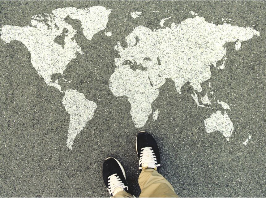 World map on an asphalt road. Top view of the legs and shoes. POV